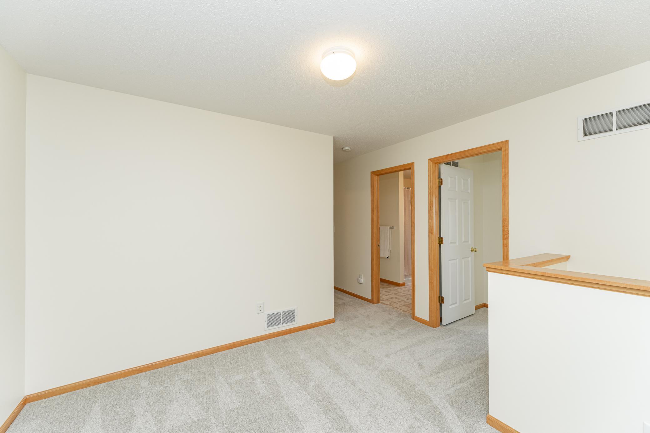 Empty carpeted room with wood trim, open doorways, and a half wall.