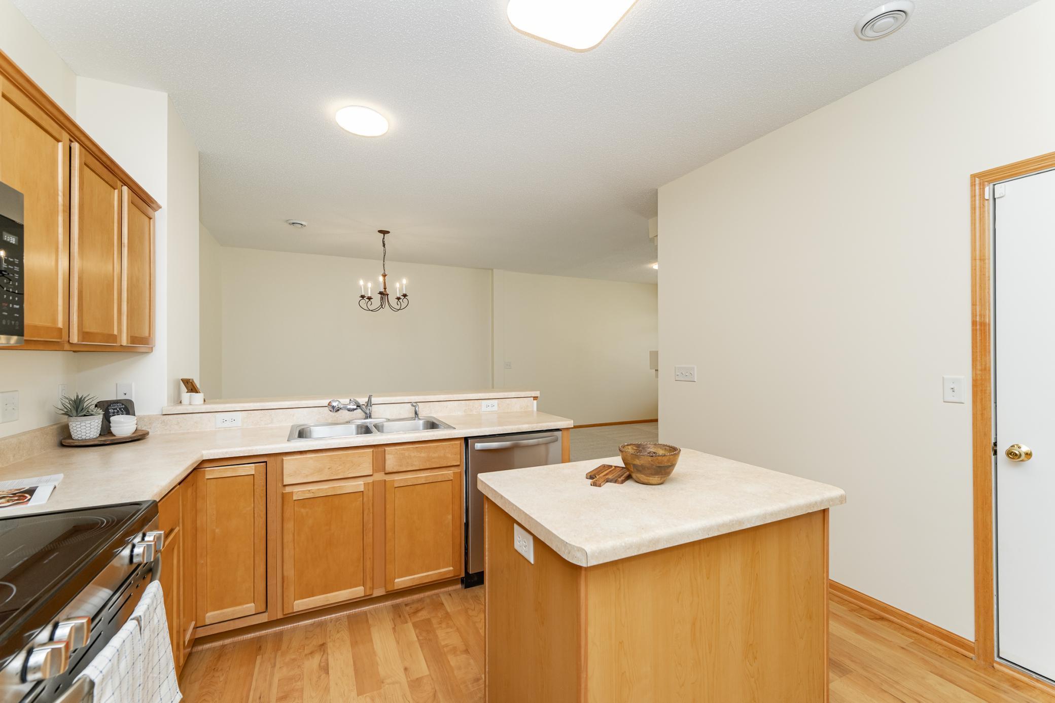 Kitchen with warm wood cabinetry, a central island, and dining area beyond.
