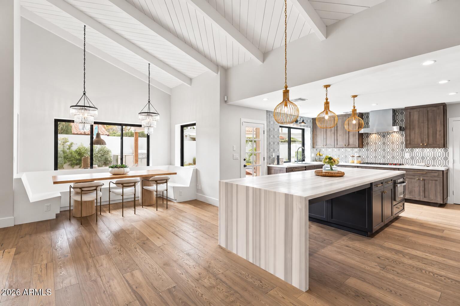 Open kitchen and dining area with a large island, vaulted ceiling, and window-side dining nook.