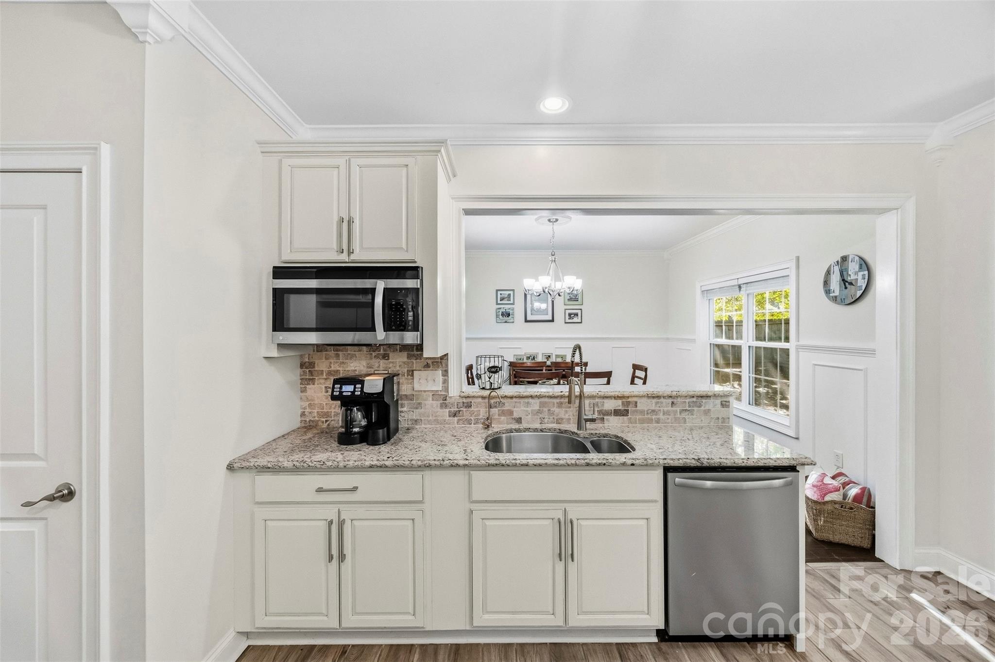 White kitchen with granite counters, stainless appliances, and a pass-through to the dining area.