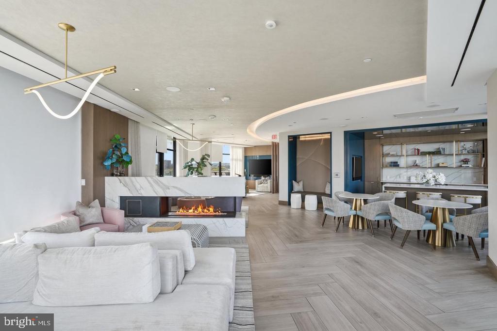 Building lounge with white sofas, a marble fireplace, and dining tables.