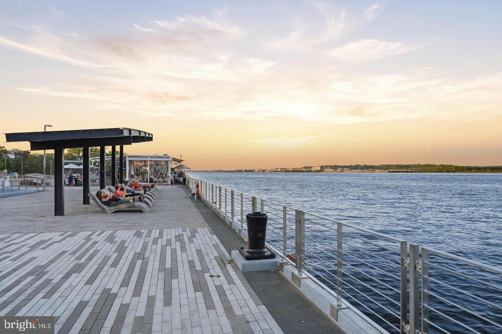 Waterfront promenade at sunset, with riverside seating and a view across the water.