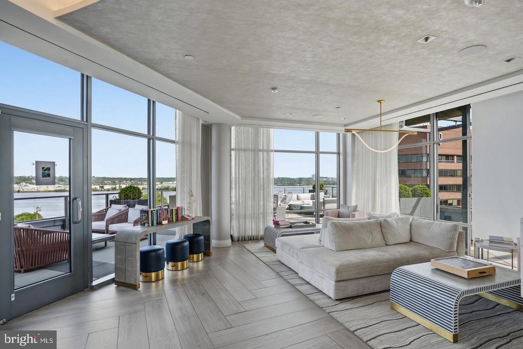 Furnished living room with floor-to-ceiling windows overlooking the river and terrace.