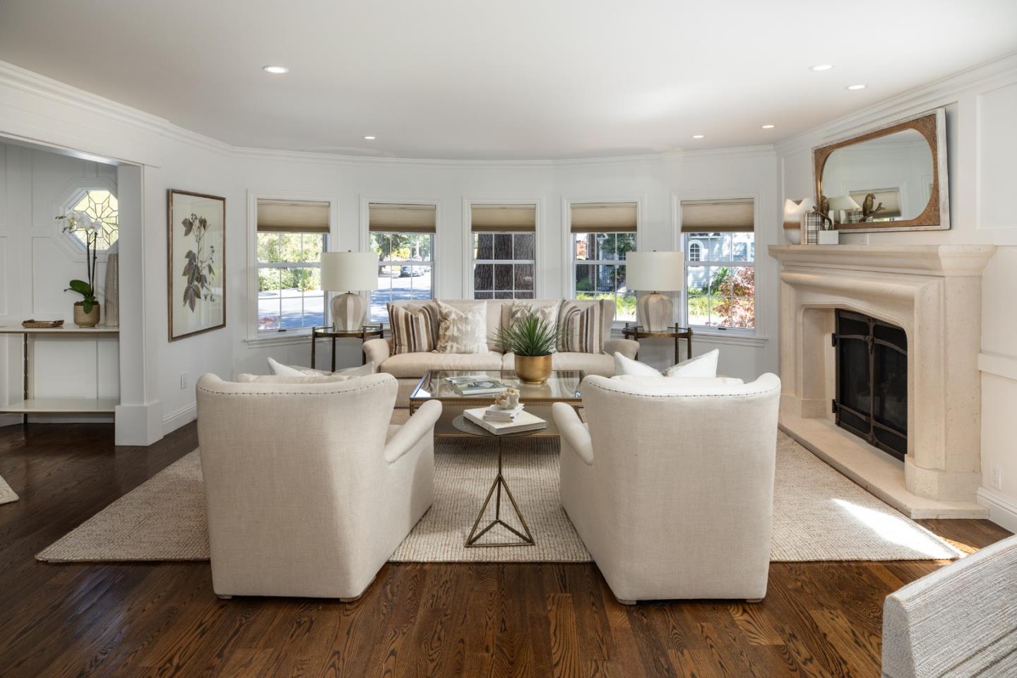 Staged living room with cream seating, a large fireplace, and dark hardwood floors.
