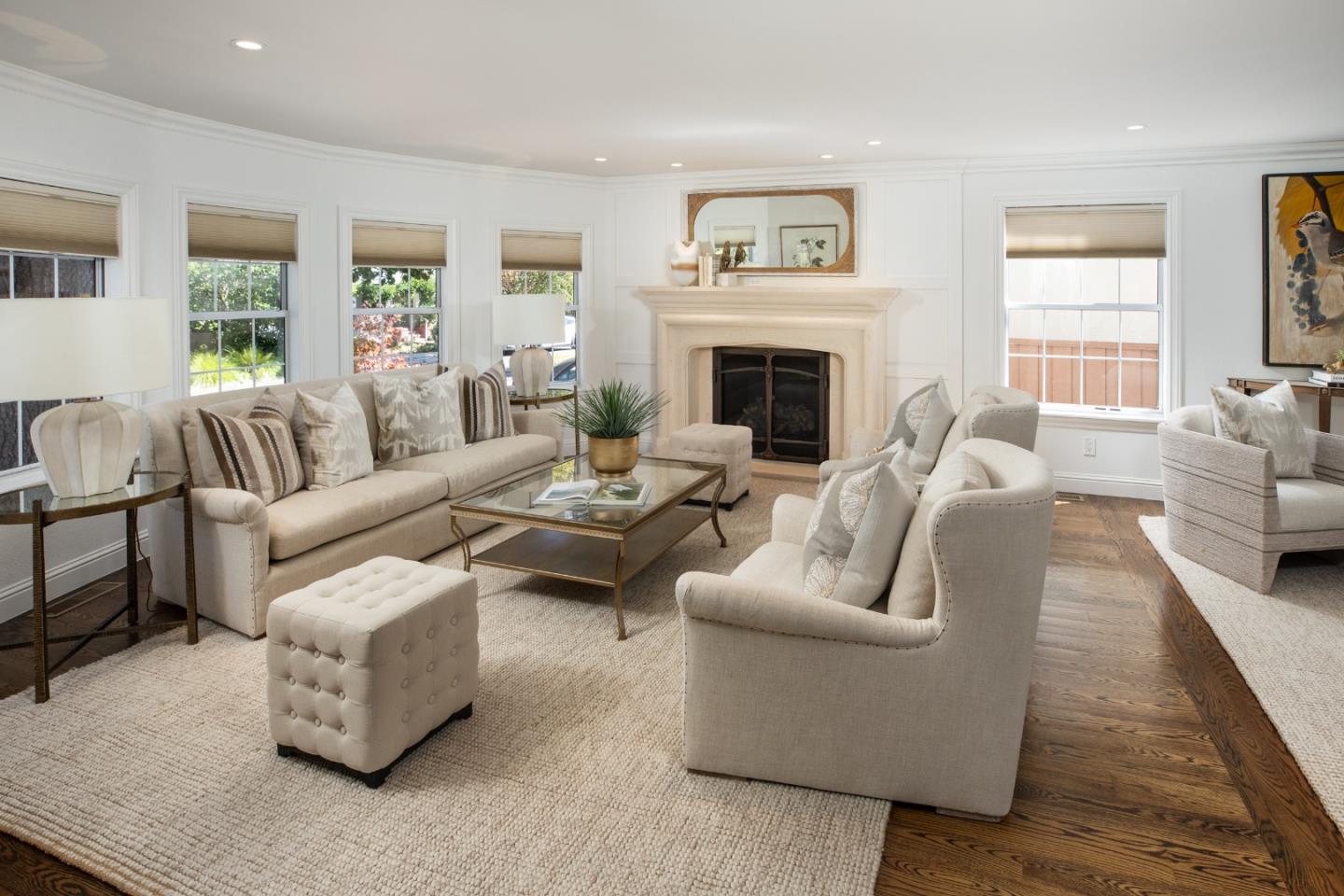 Living room with a central fireplace, cream seating, and hardwood floors.