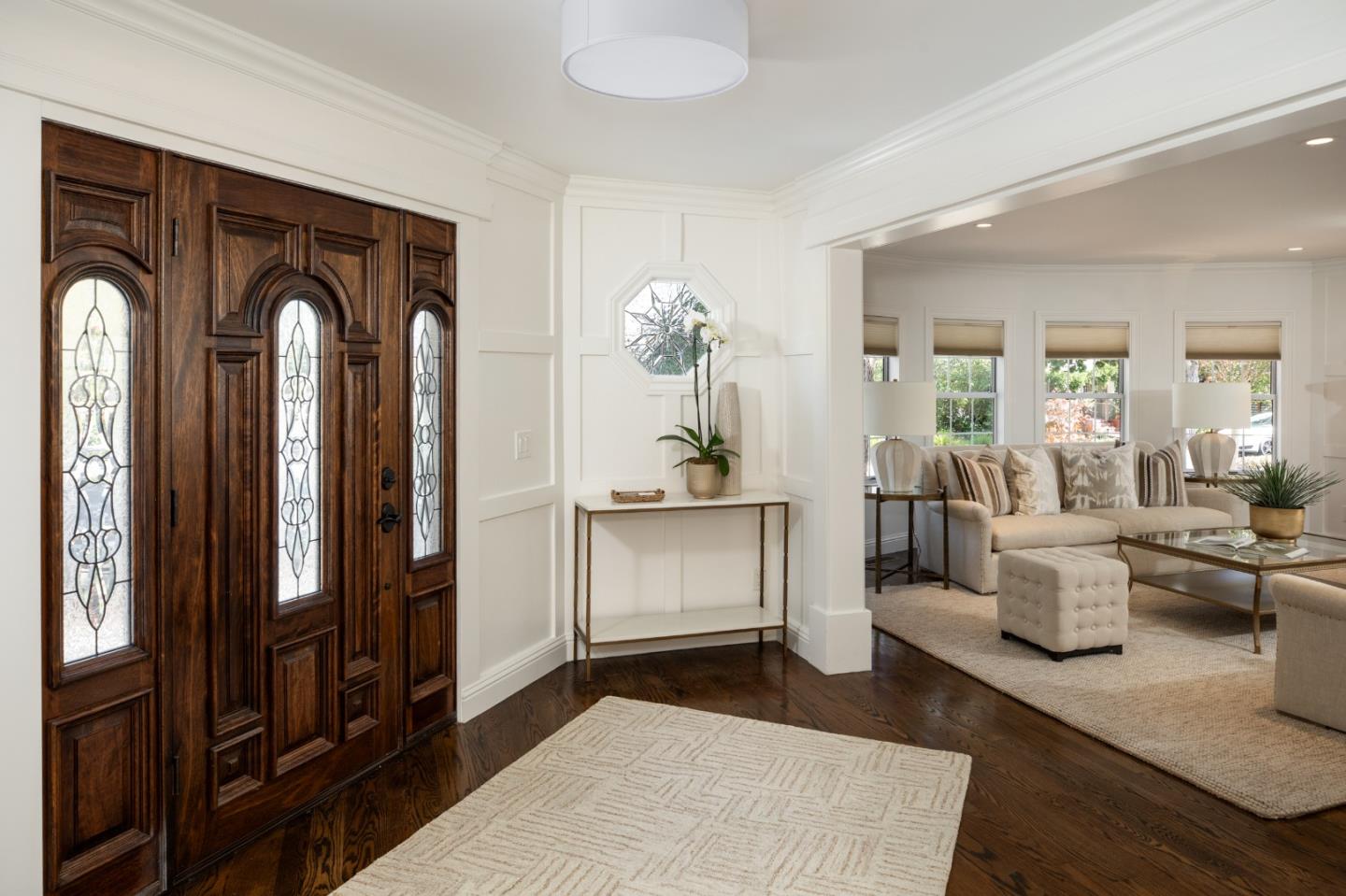 Entryway with a carved wood front door opening into a bright living room.
