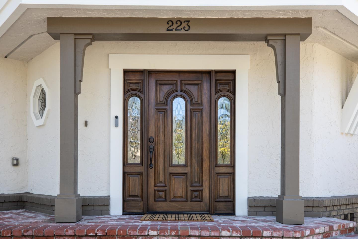 Front entrance with an ornate stained-glass wooden door and brick steps.