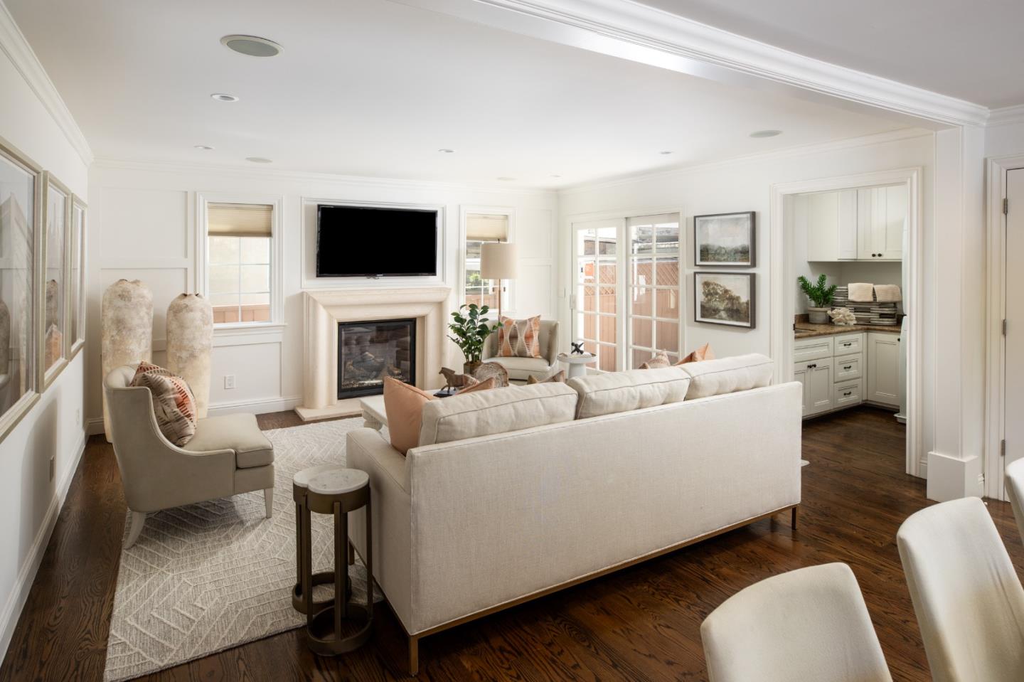 Staged living room with a fireplace, mounted TV, French doors, and dark hardwood floors.