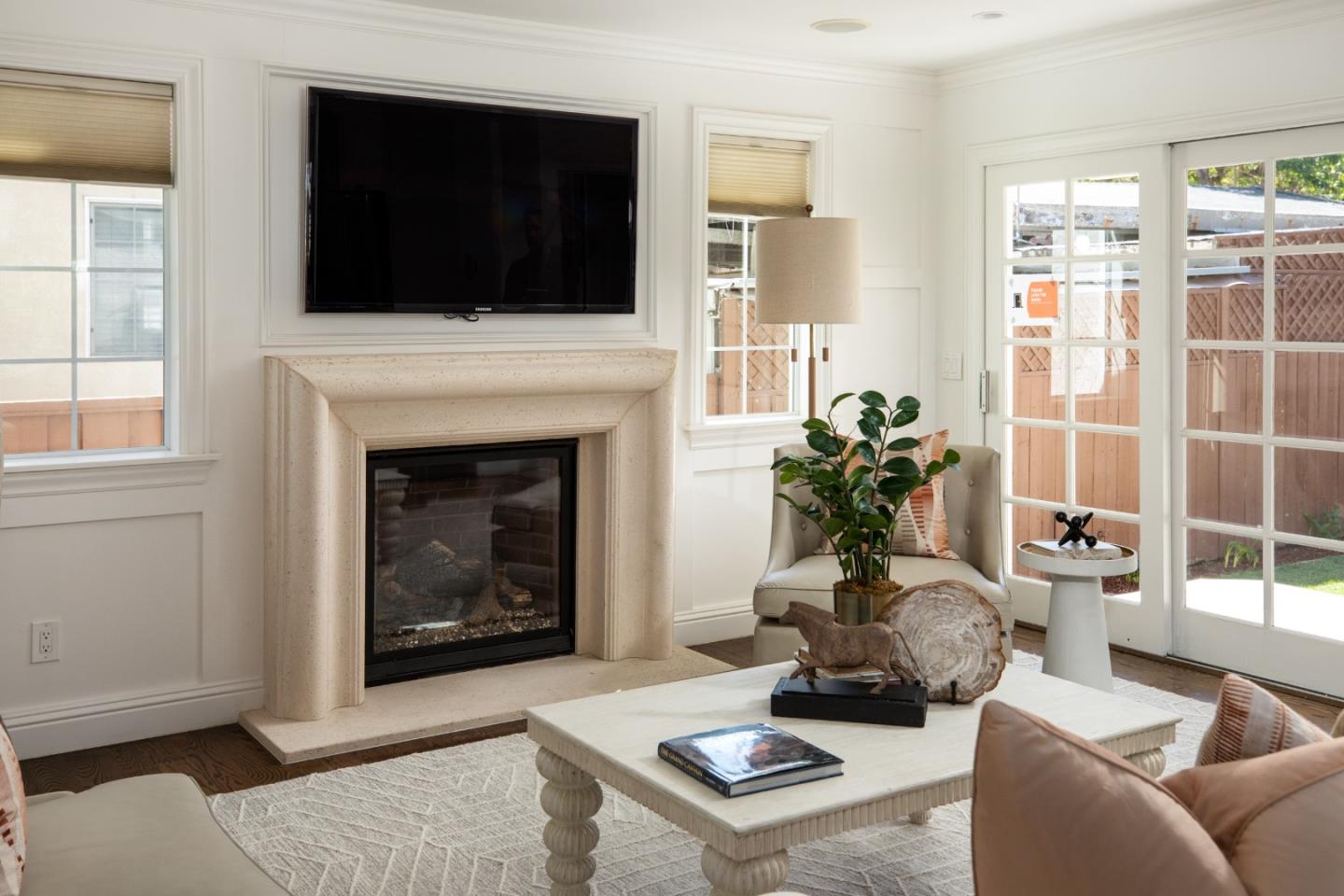 Living room with a stone fireplace, mounted television, and glass doors to the yard.