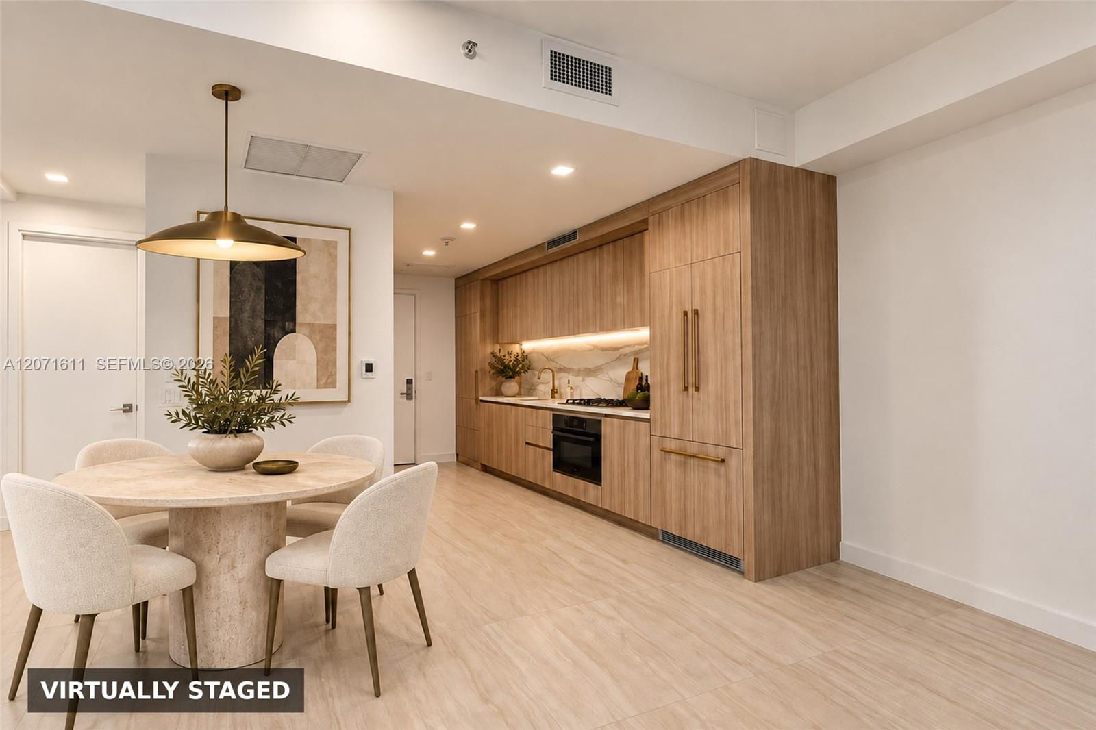 Dining area and kitchen with a round stone table and warm wood cabinetry.