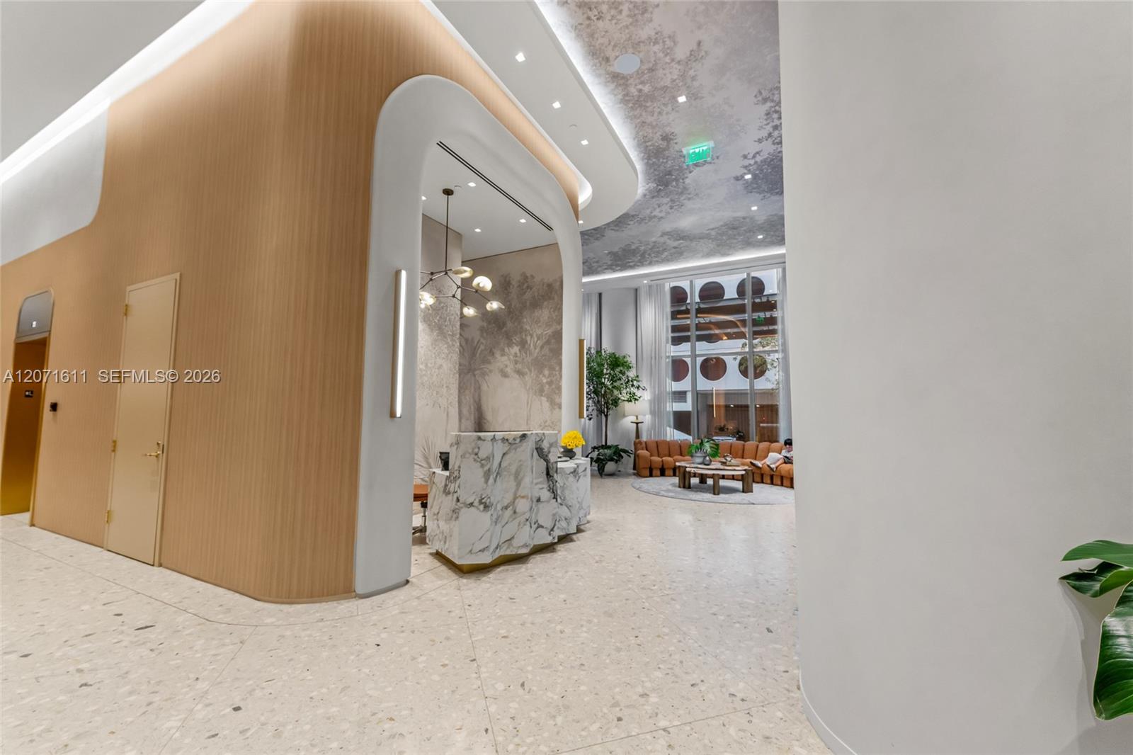 Modern condominium lobby with a curved wood-paneled reception area and marble-fronted desk.