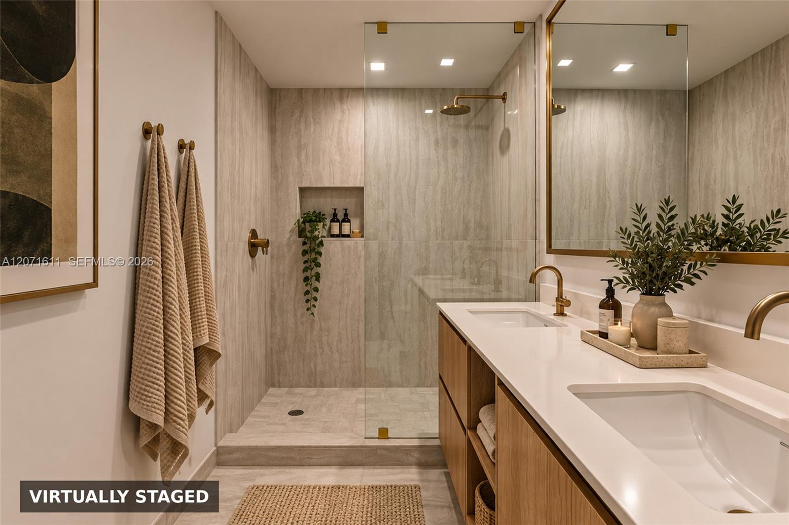Bathroom with a glass walk-in shower and double vanity with brass fixtures.