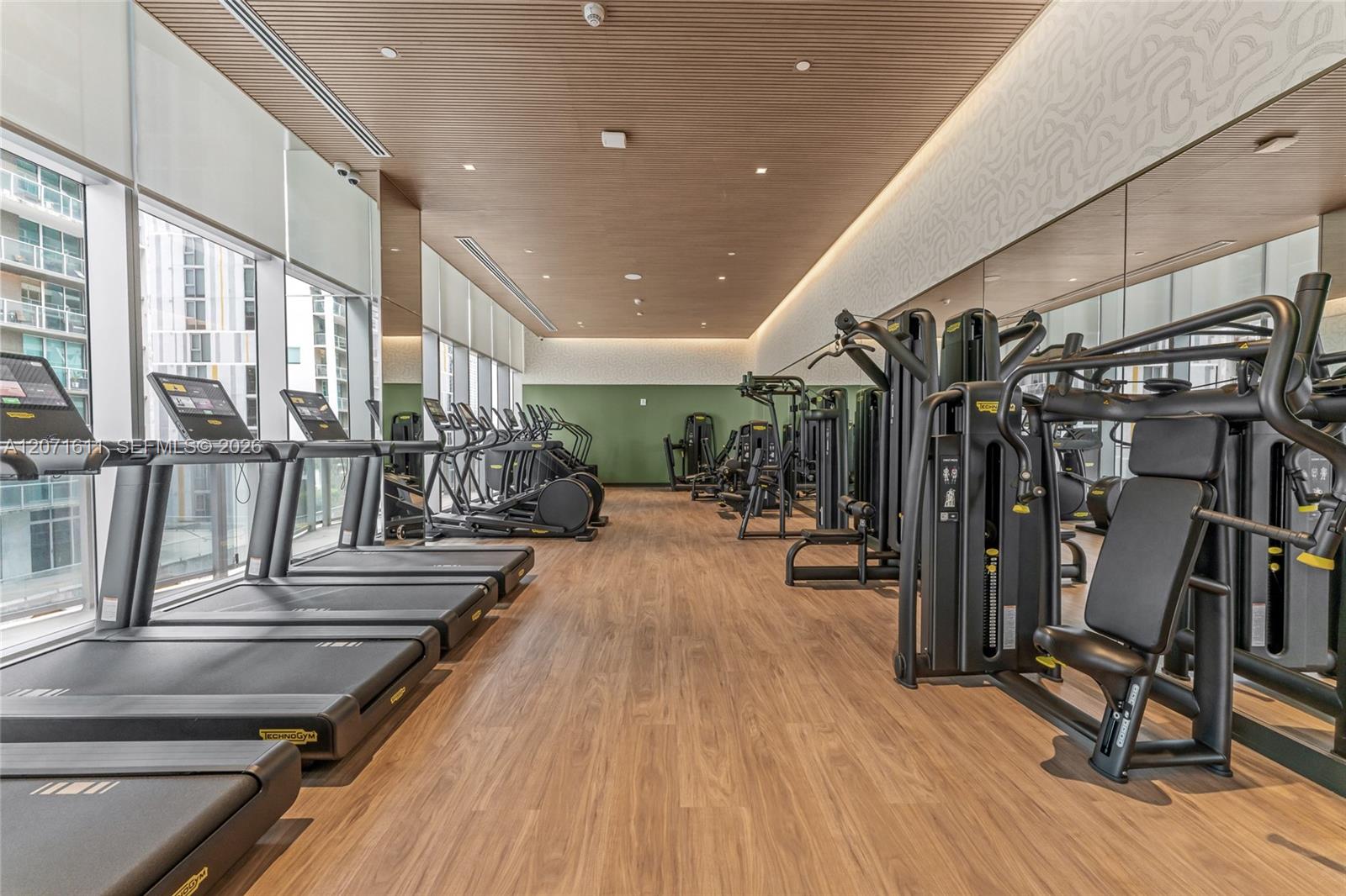 Fitness room with treadmills along tall windows and weight machines.