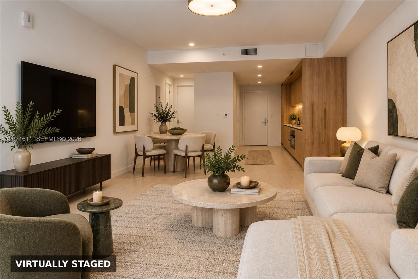 Virtually staged condo living room with a cream sofa, round coffee table, and adjoining dining area.