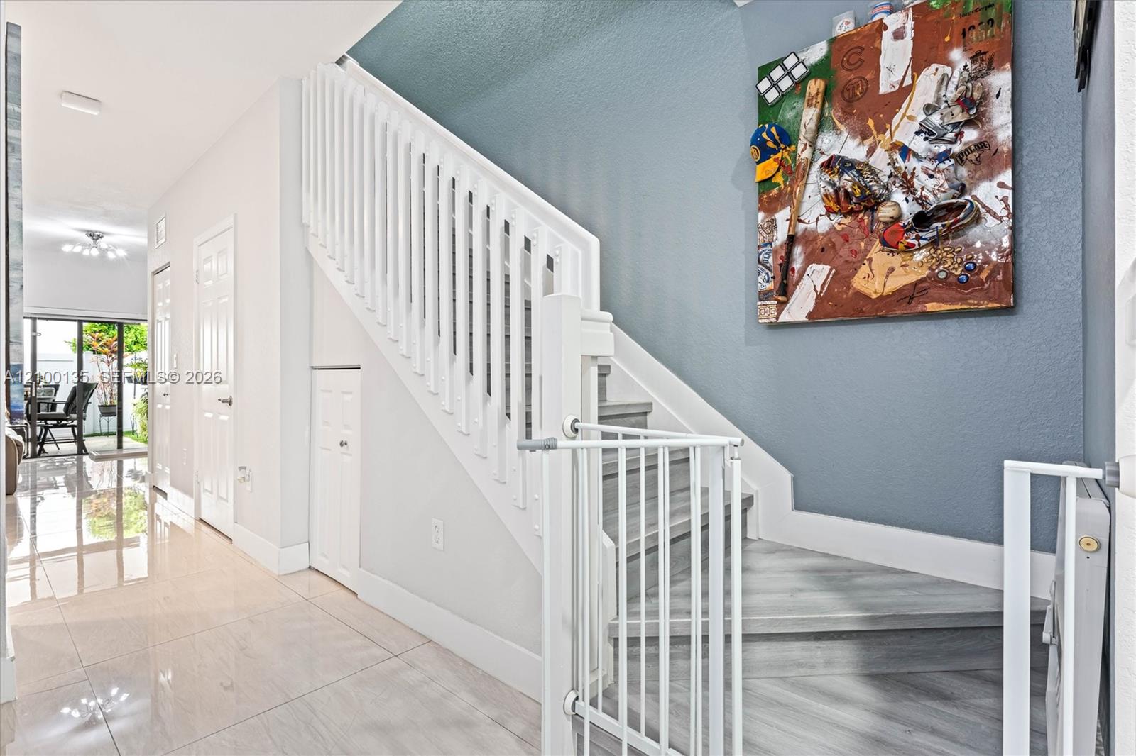 Gray staircase with white railings beside a blue wall and tiled hallway.