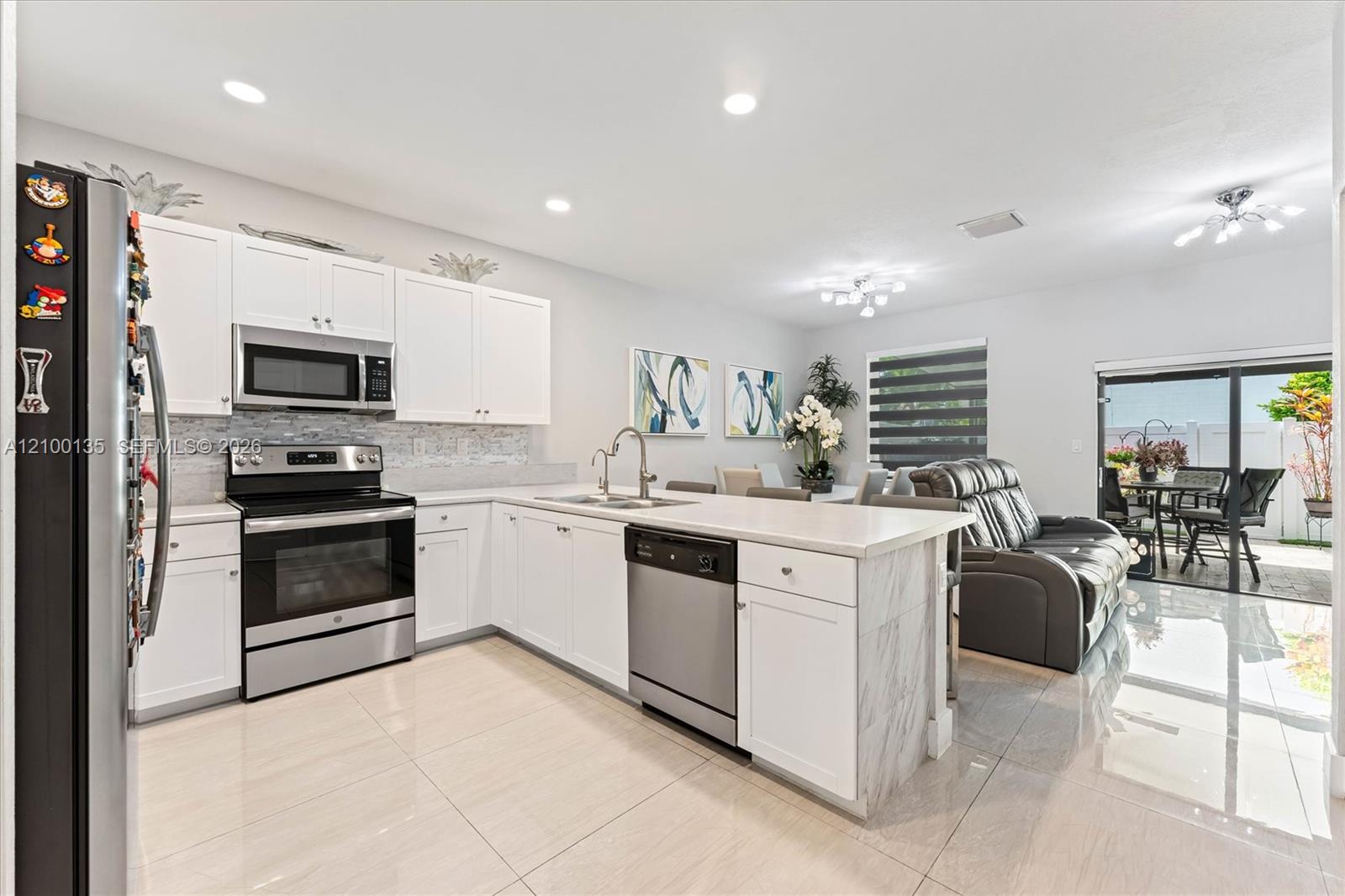 Open-plan kitchen with white cabinetry, a large island, stainless steel appliances, and sliding doors to a patio.