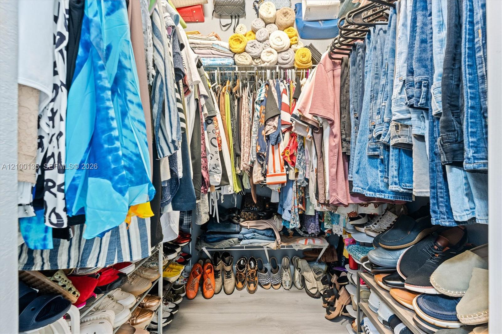 Walk-in closet packed with hanging clothes and shelves of shoes.
