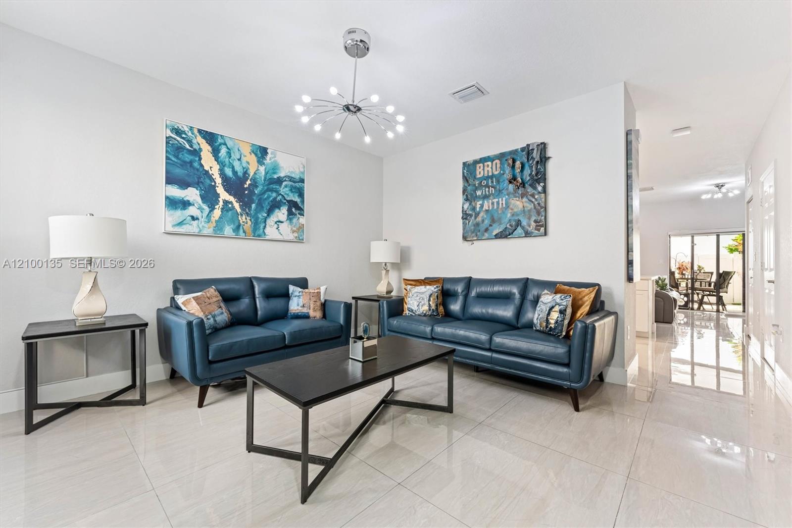 Living room with teal leather sofas, a black coffee table, and glossy tile floors.