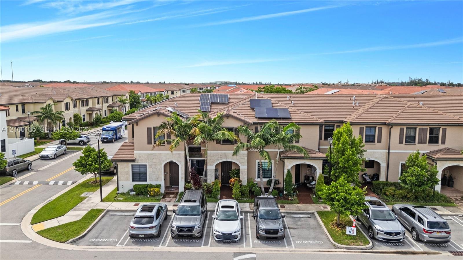 Aerial view of attached townhomes with solar panels and reserved parking.