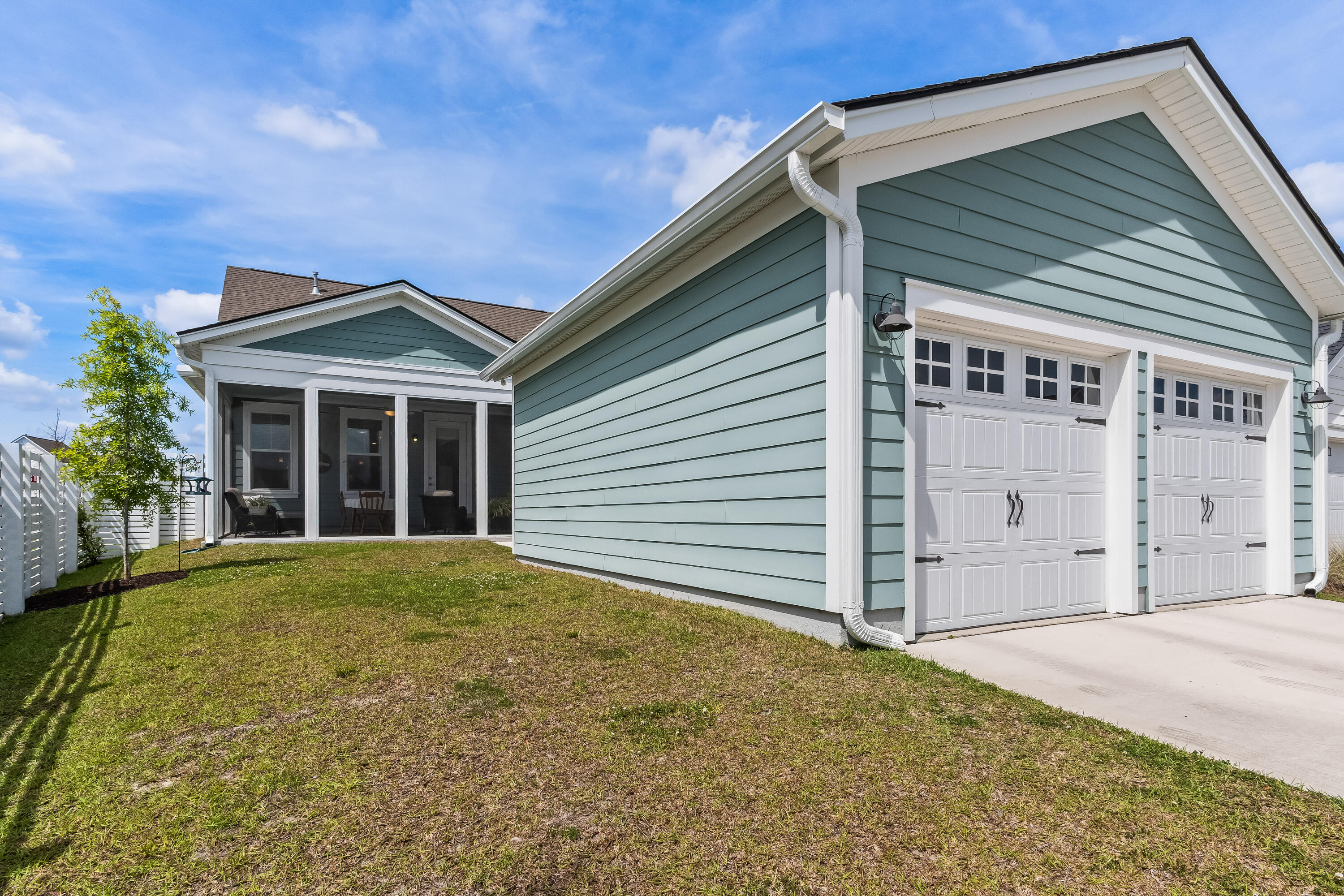 Blue-gray house with two white garage doors and a screened patio at the rear.