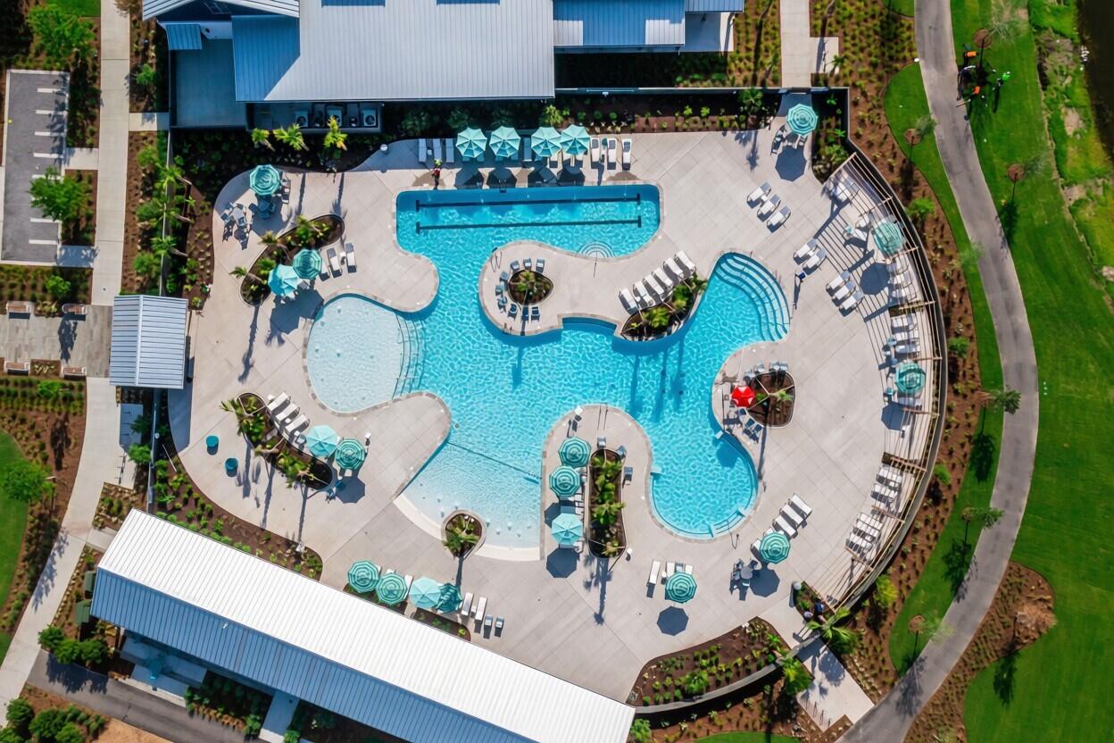 Aerial view of a resort-style pool complex with connected pools and turquoise umbrellas.