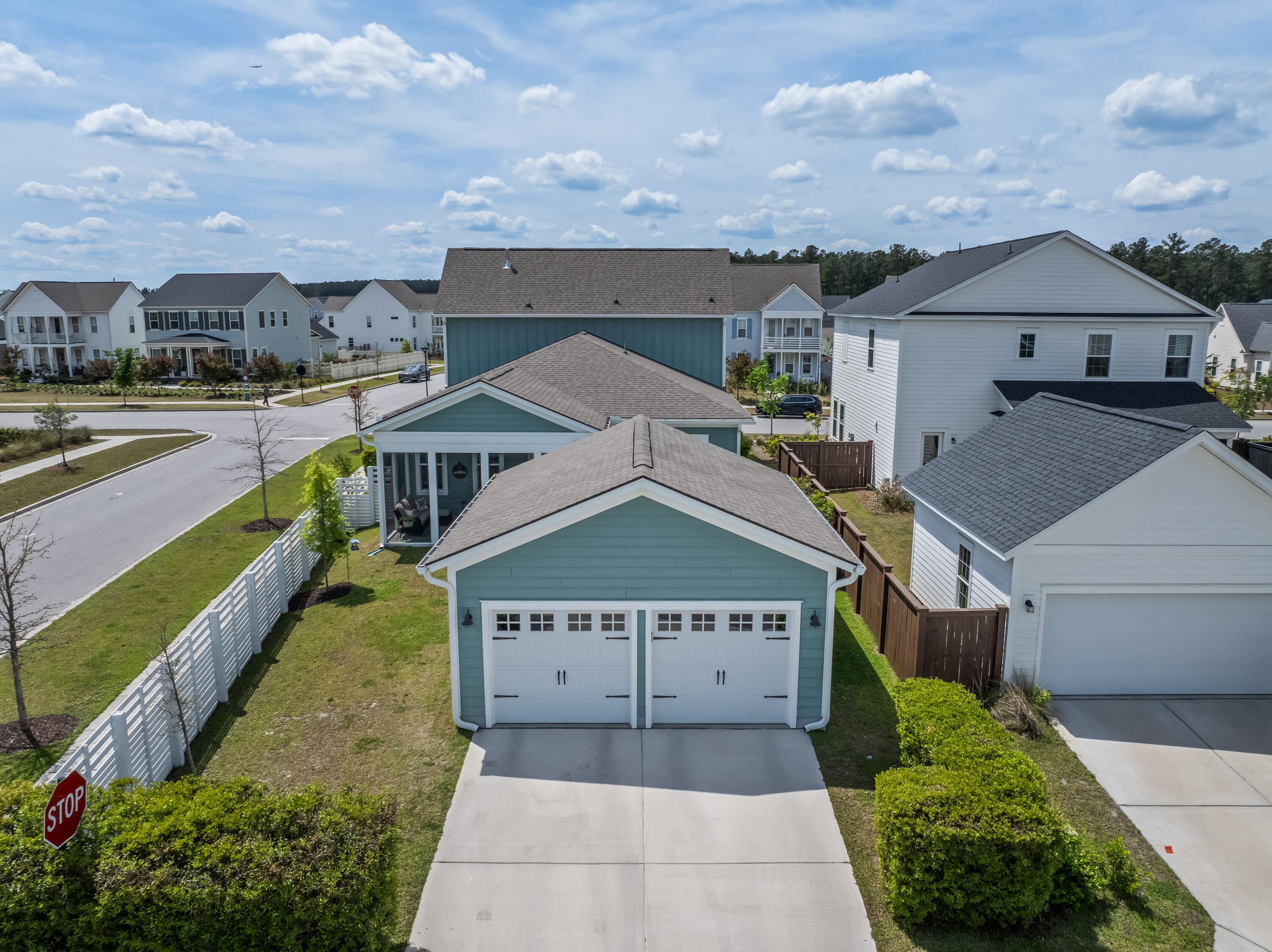 Aerial view of a blue home with a two-car garage, fenced yard, and neighboring houses.