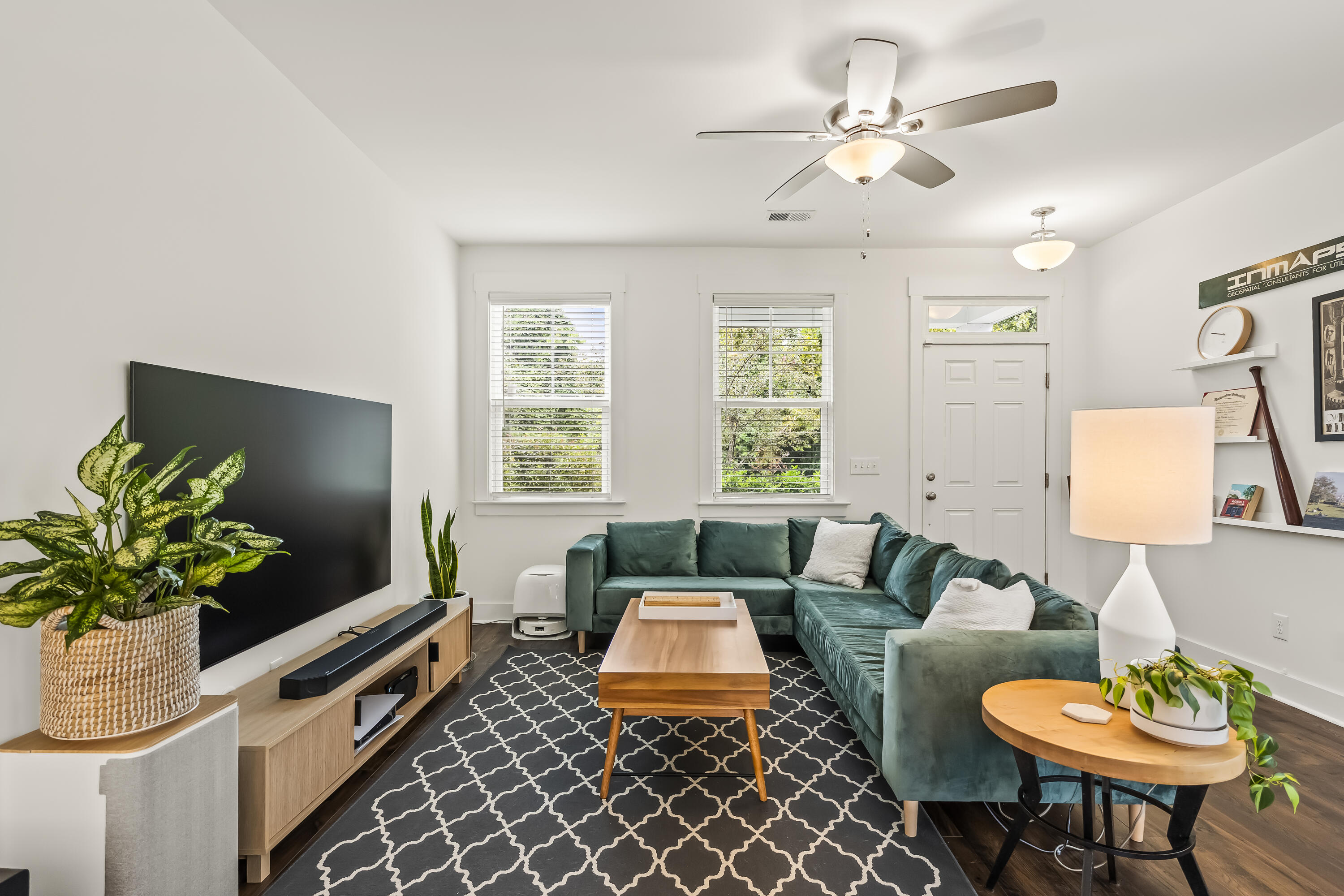 Living room with a teal sectional, wooden coffee table, patterned rug, and large television.