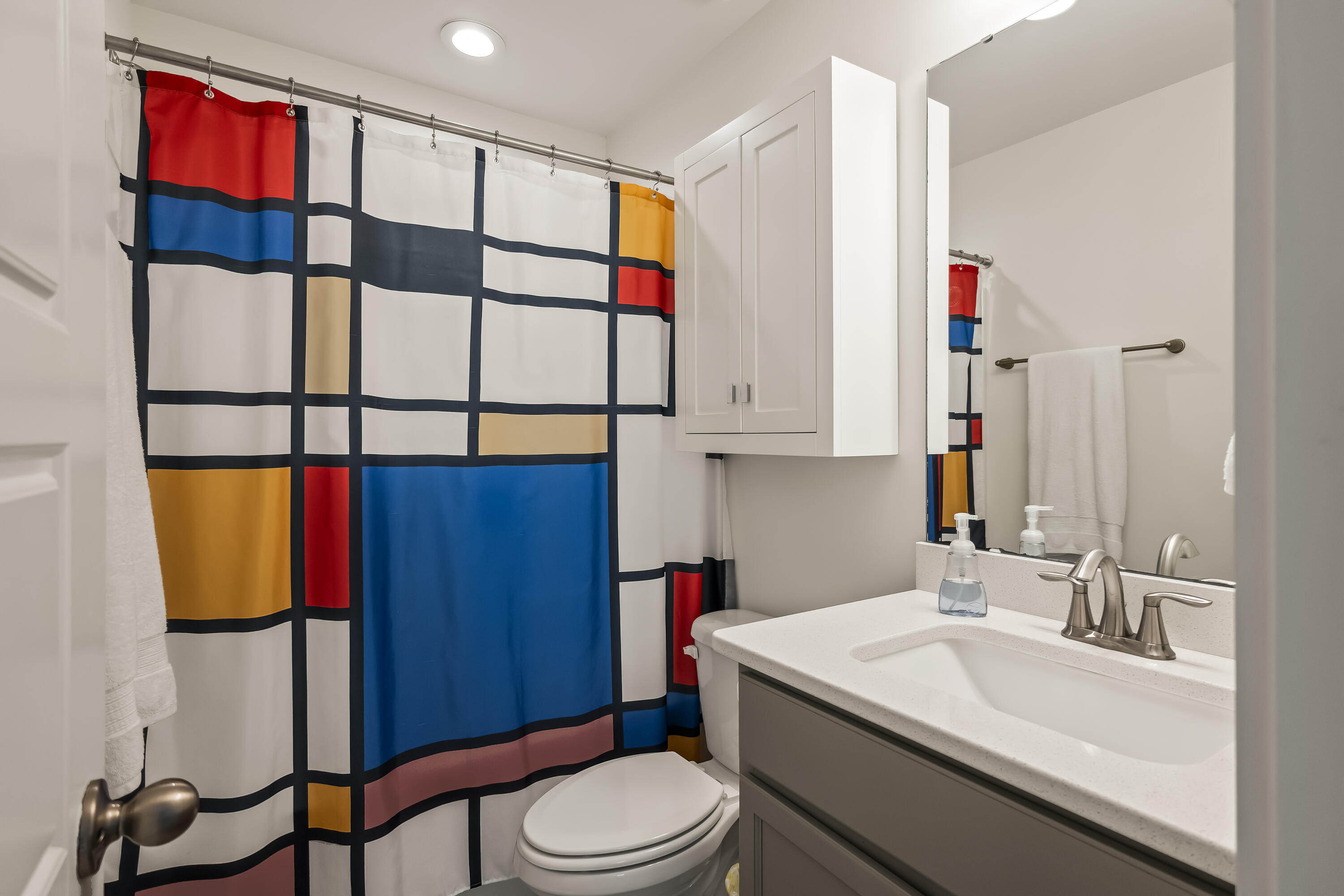 Bathroom with a colorful geometric shower curtain and white vanity.