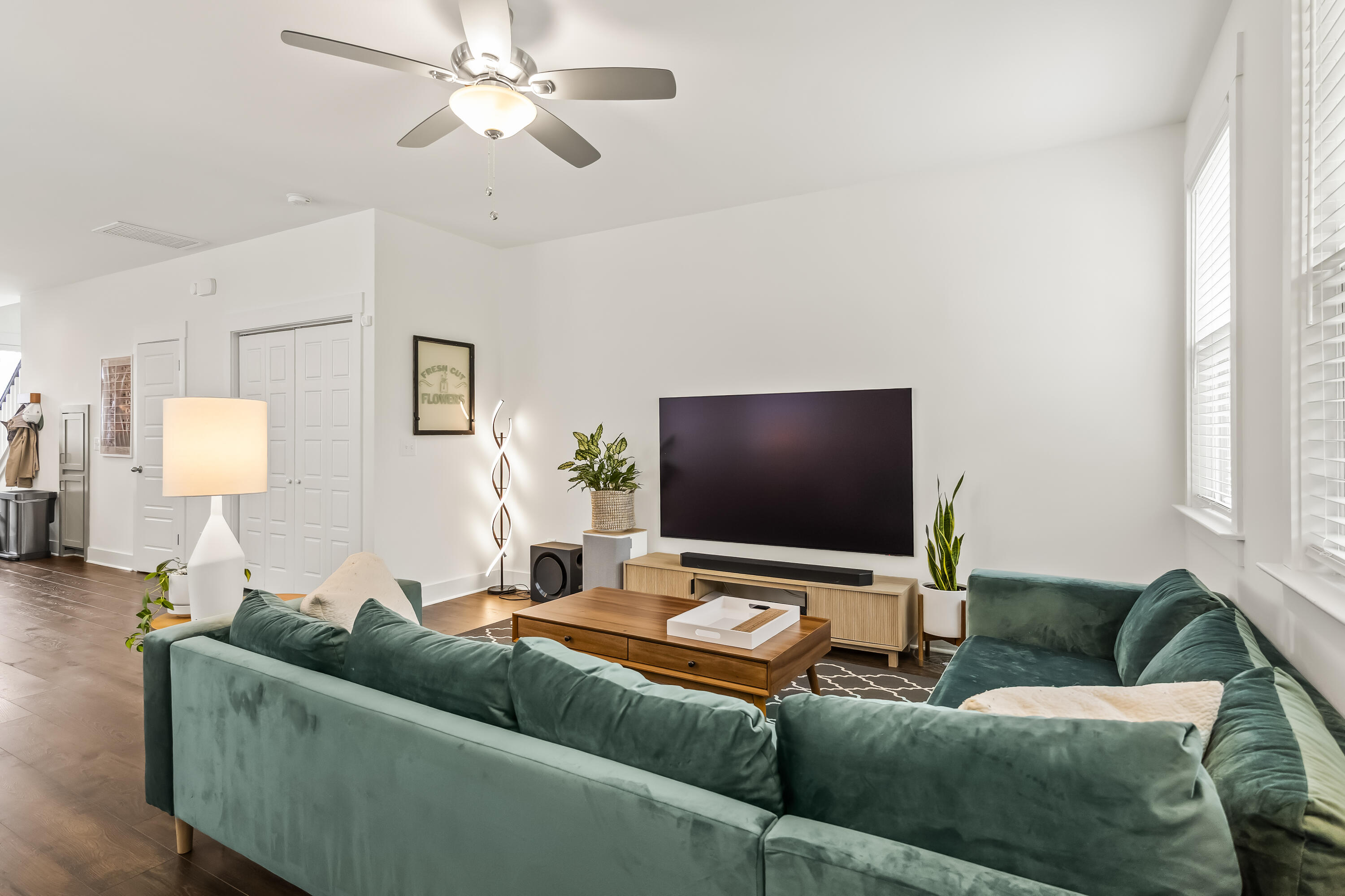 Living room with green sofas, a wooden coffee table, and a wall-mounted TV.