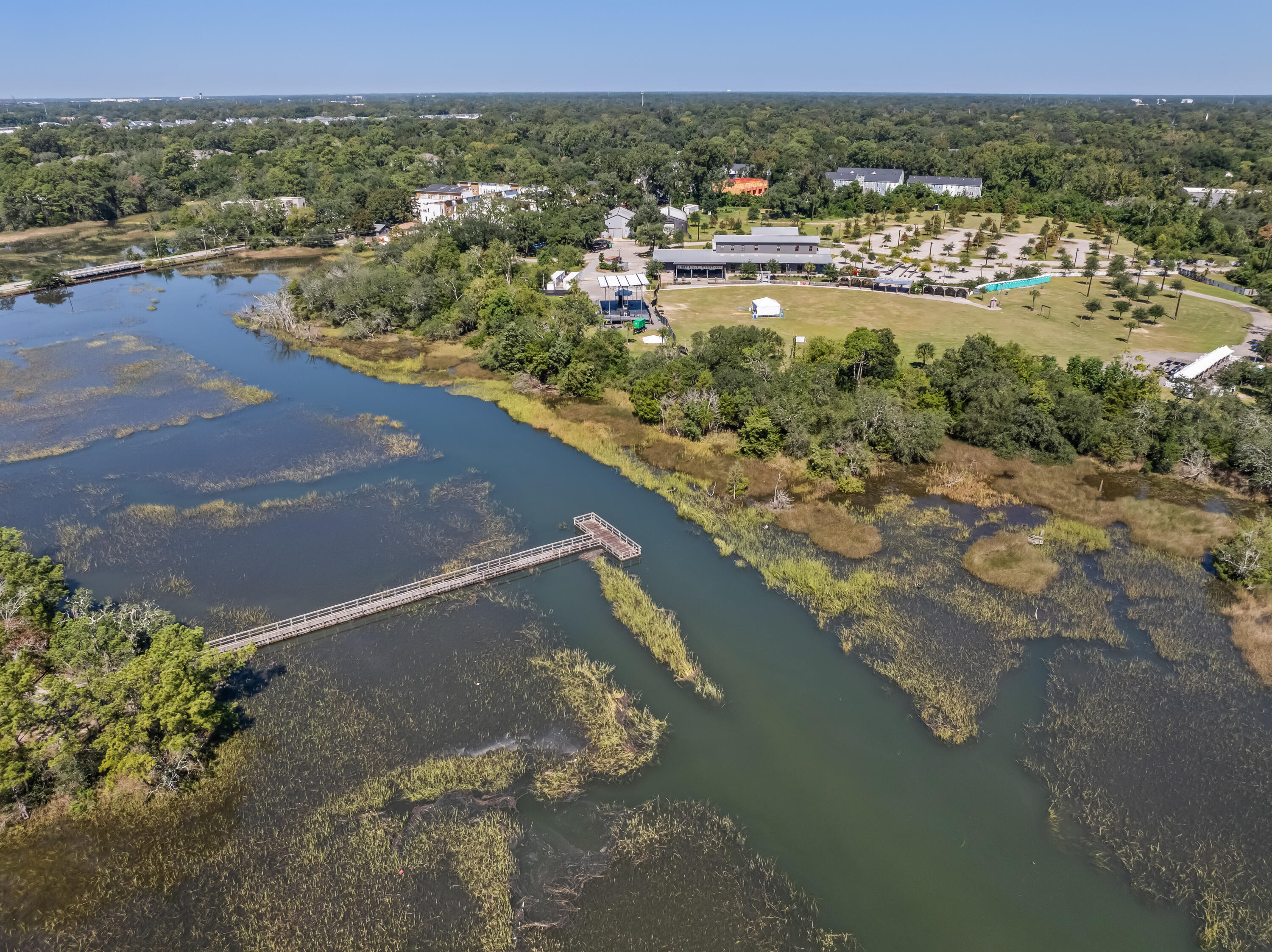Aerial view of a tidal marsh with a long wooden dock extending into the water.