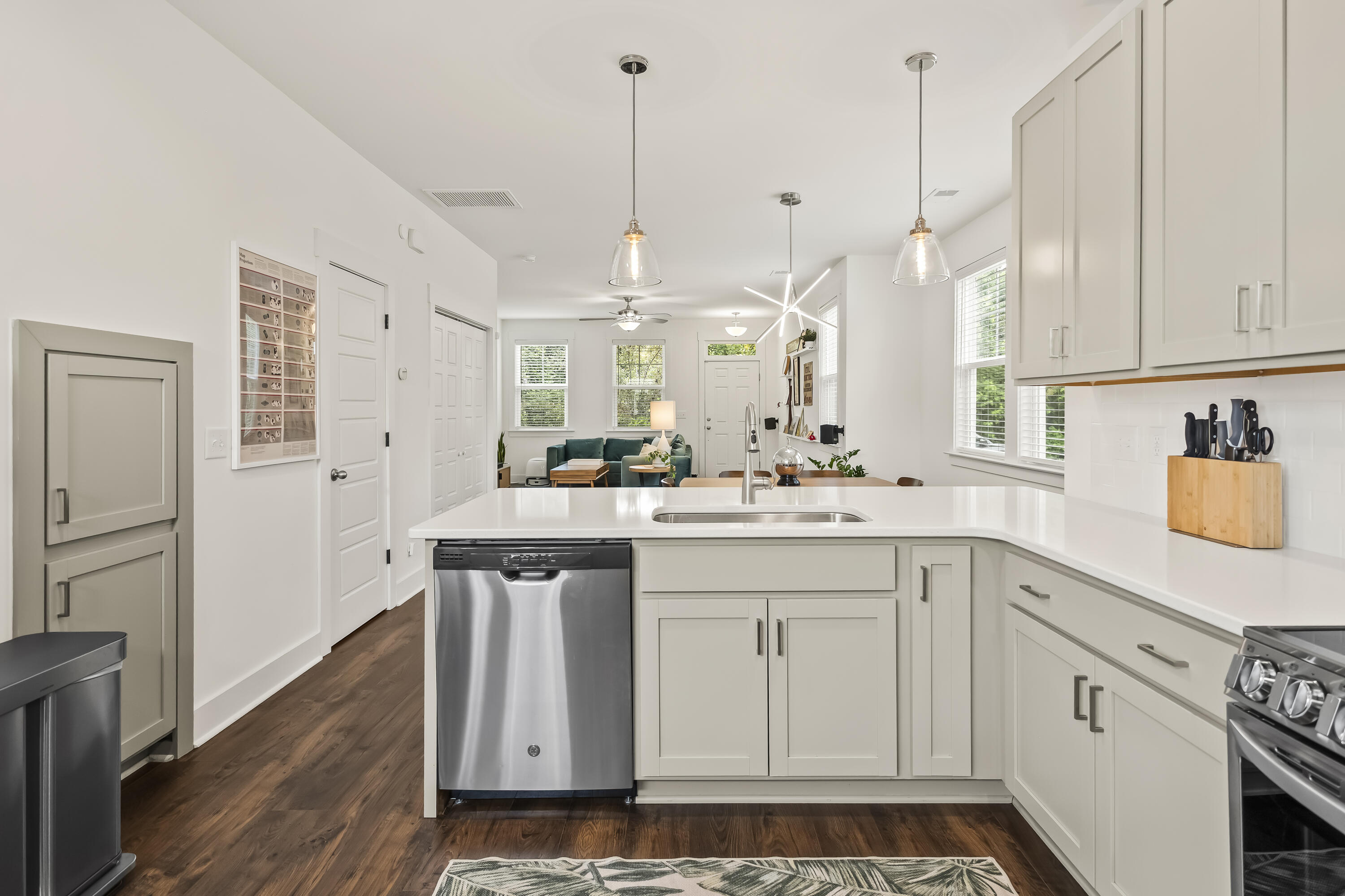 Bright white kitchen with a large peninsula, stainless appliances, and an open view into the living area.