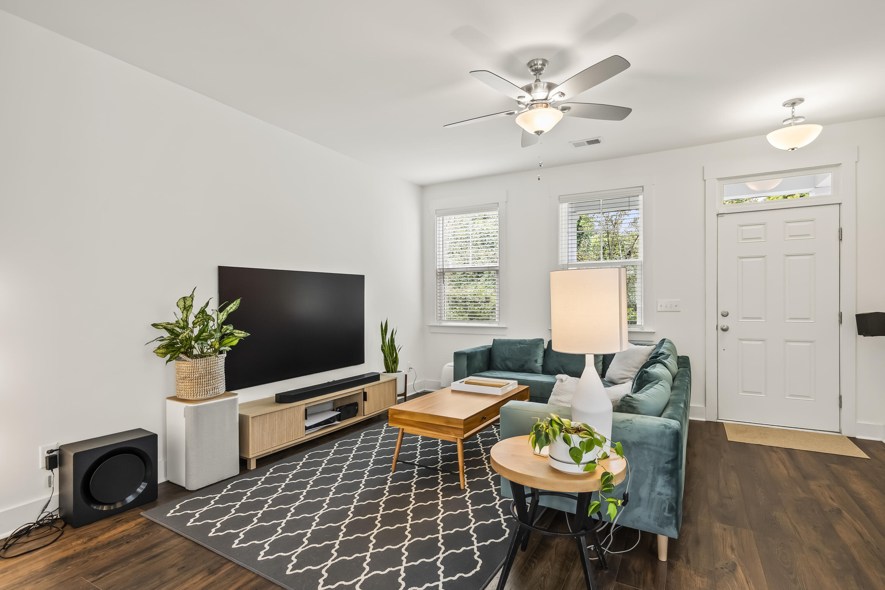 Living room with a teal sectional, wood coffee table, patterned rug, and television.
