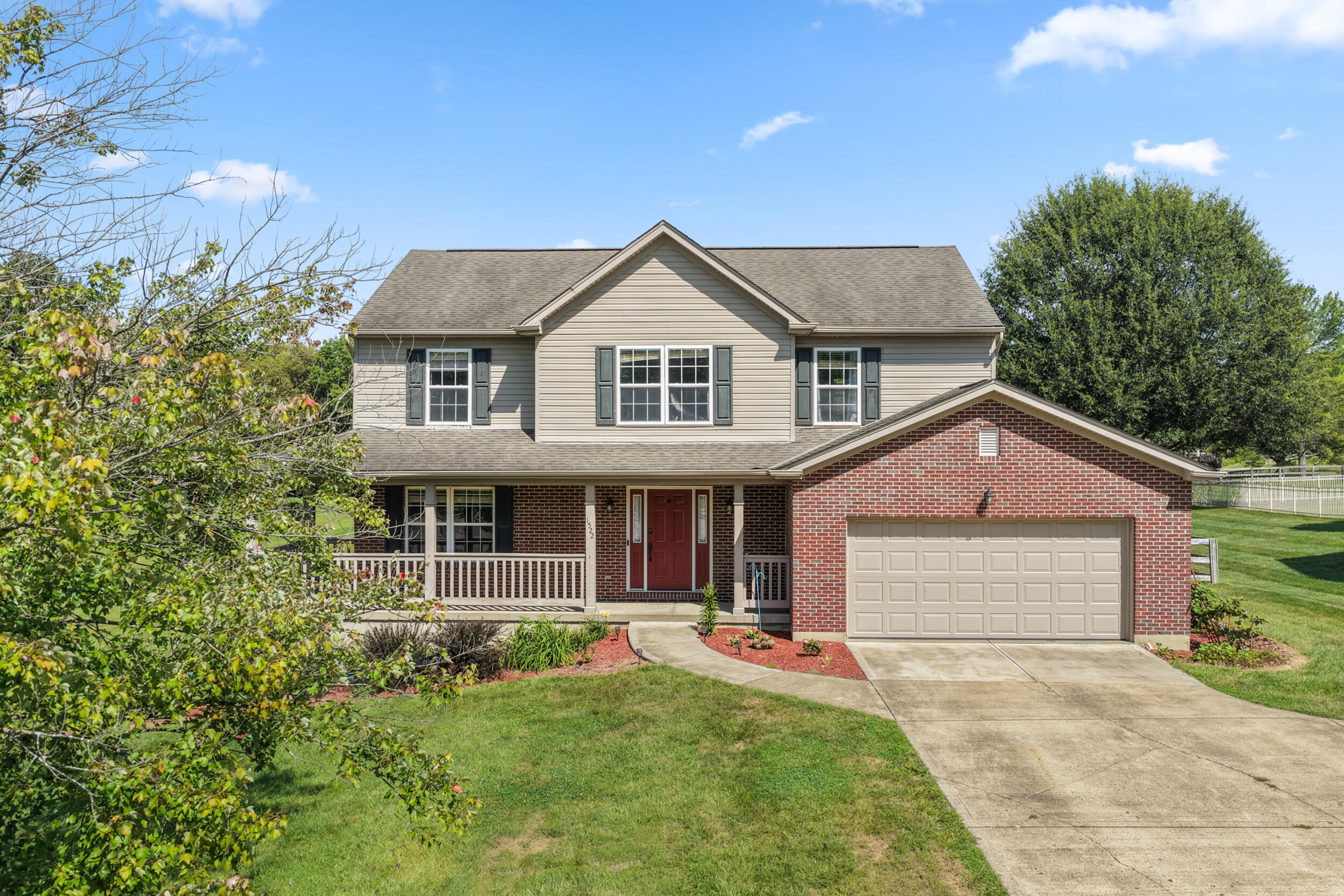 Two-story home with a brick facade, covered porch, and attached two-car garage