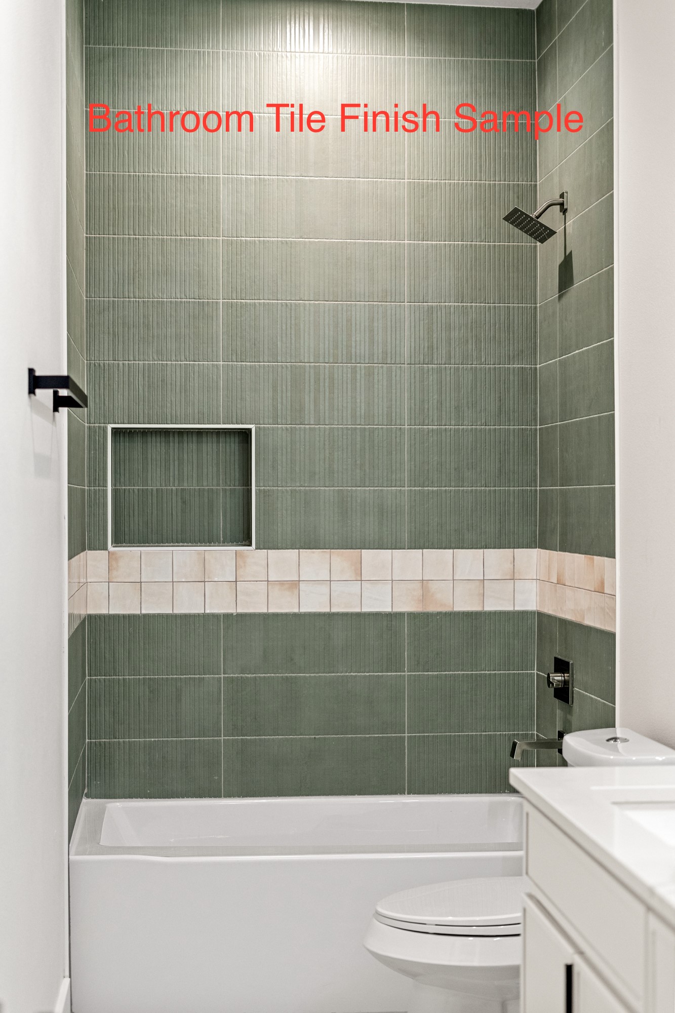 Bathroom with a white tub and toilet, sage-green ribbed shower tile, and a pale accent band.