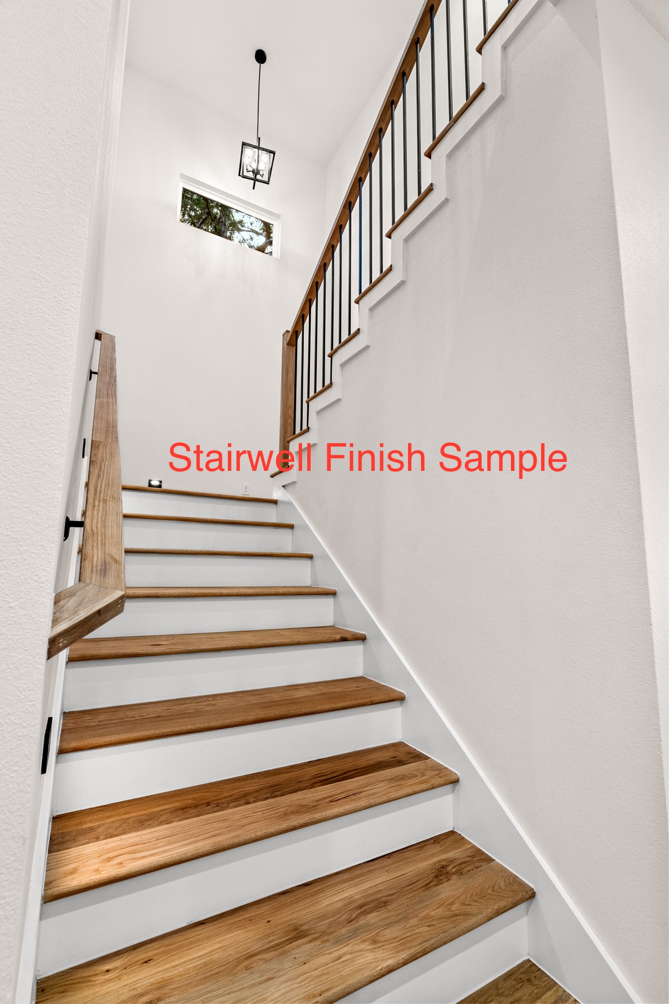 Interior stairwell with wood treads, white risers, and black metal railing with a wood handrail.