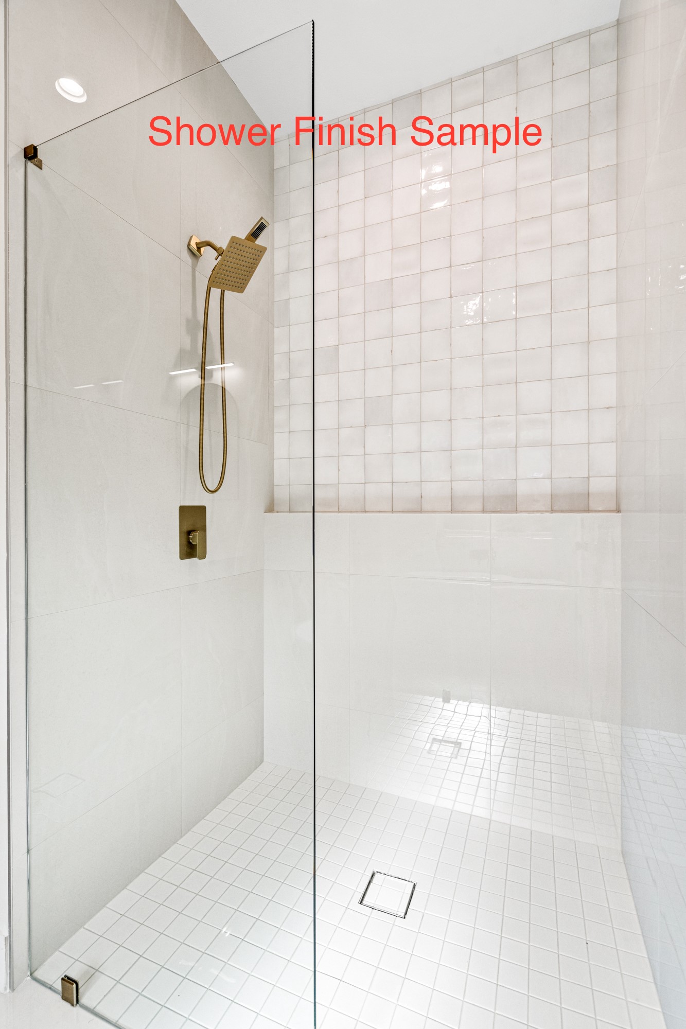 Walk-in shower with white tile, clear glass enclosure, and brushed brass fixtures.