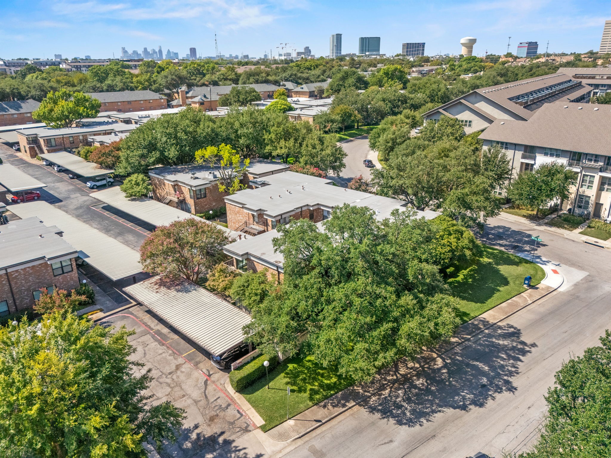 Aerial view of a low-rise residential complex with Dallas skyline in the distance.