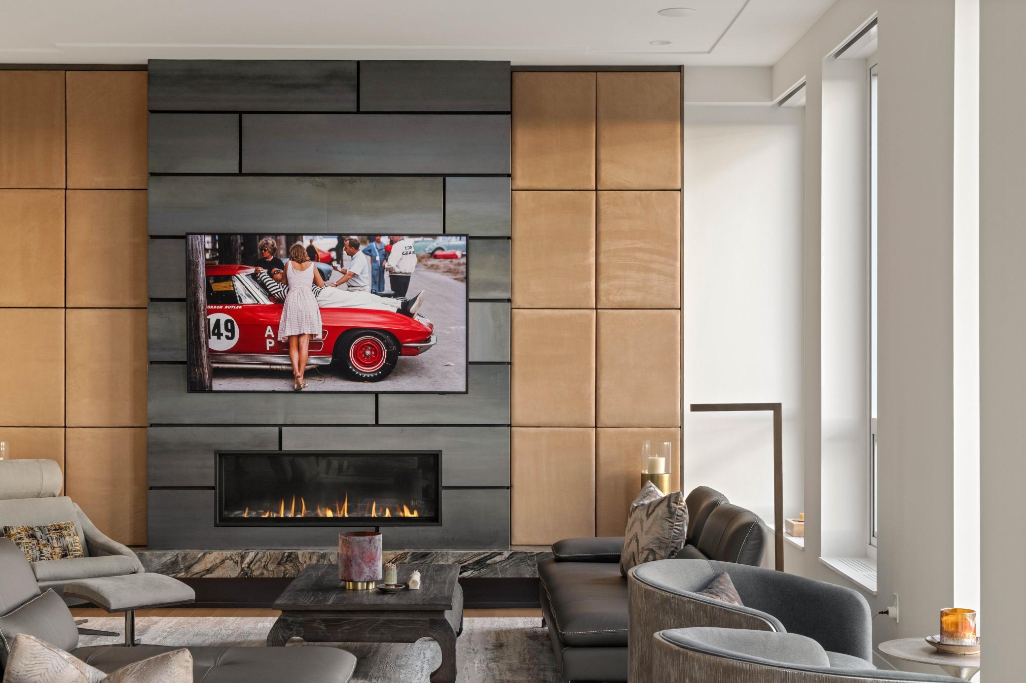 Modern living room with a linear fireplace, charcoal feature wall, warm wood panels, and tall windows.