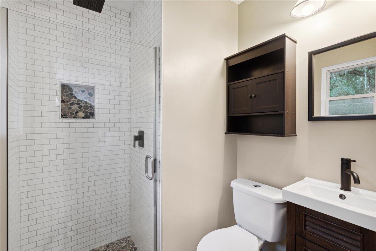 Bathroom with a white subway-tile shower, pebble-stone niche, and dark wood vanity.