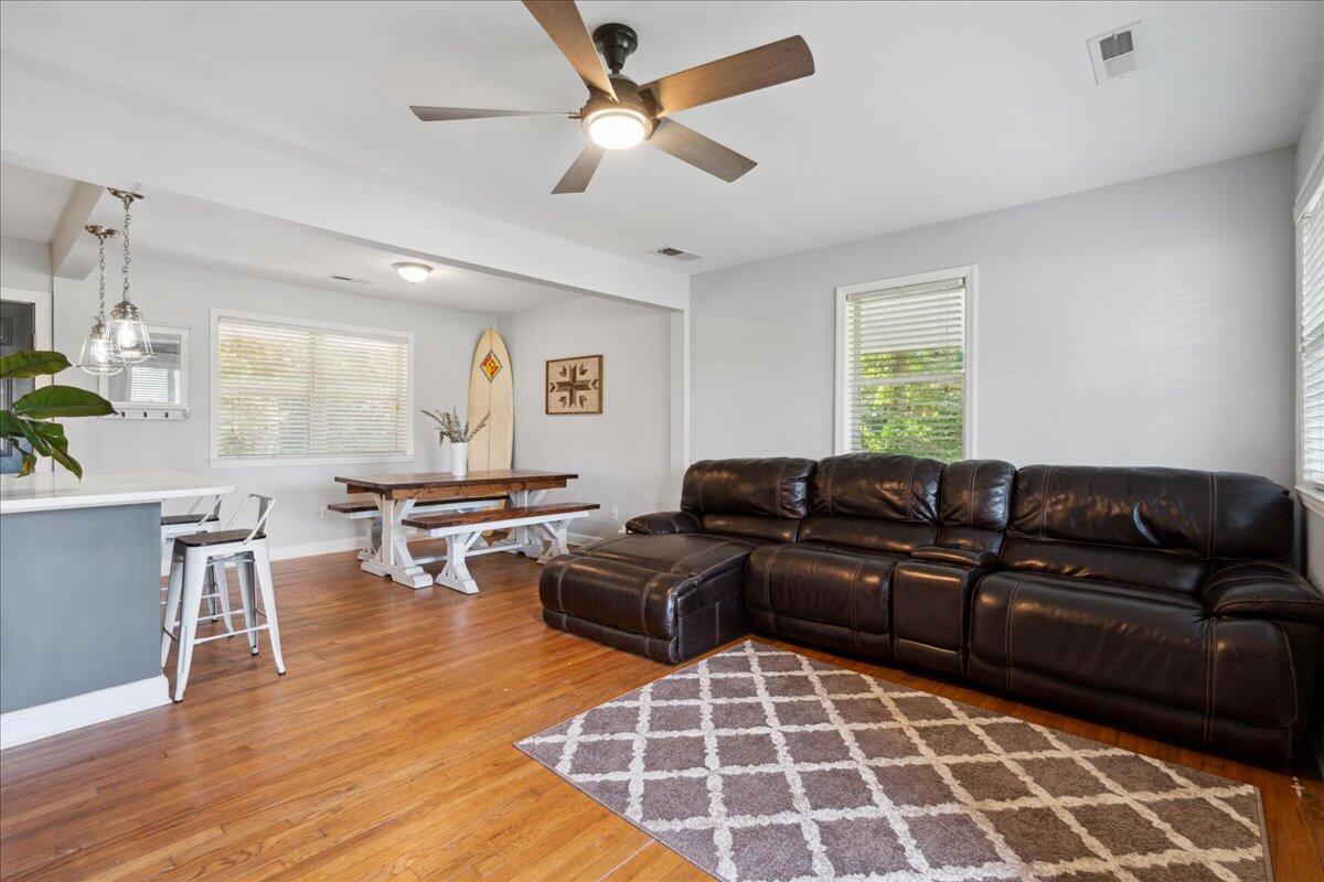 Living room with a dark leather sectional, patterned rug, hardwood floors, and an open dining area.