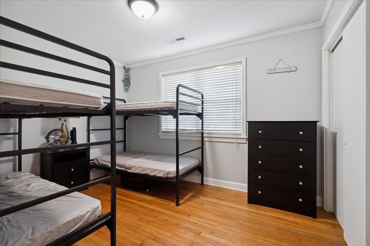 Bedroom with black metal bunk beds, a dark dresser, and hardwood floors.