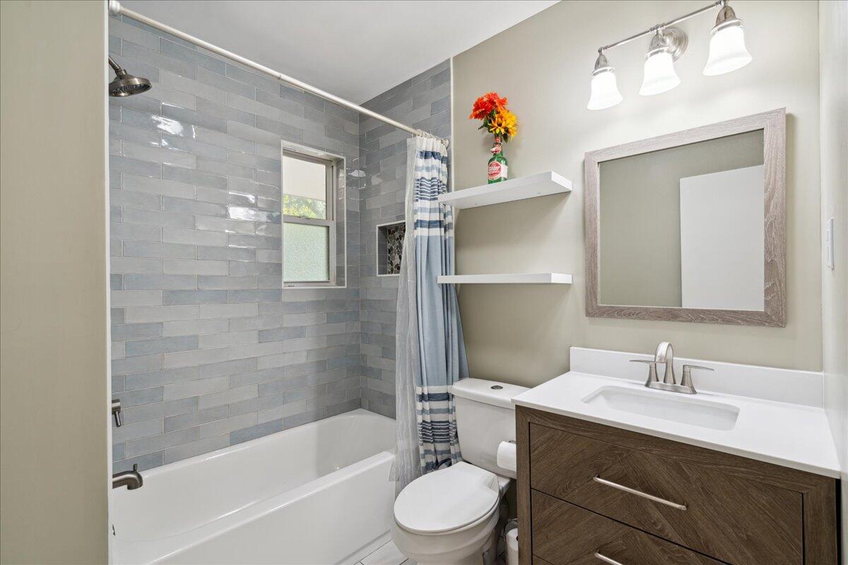 Bathroom with a gray subway tile tub surround, striped shower curtain, and dark wood vanity.