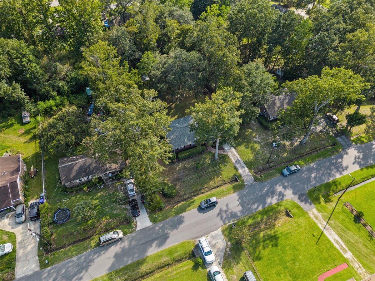 Aerial view of a leafy residential property beside a street, surrounded by mature trees and neighboring homes.