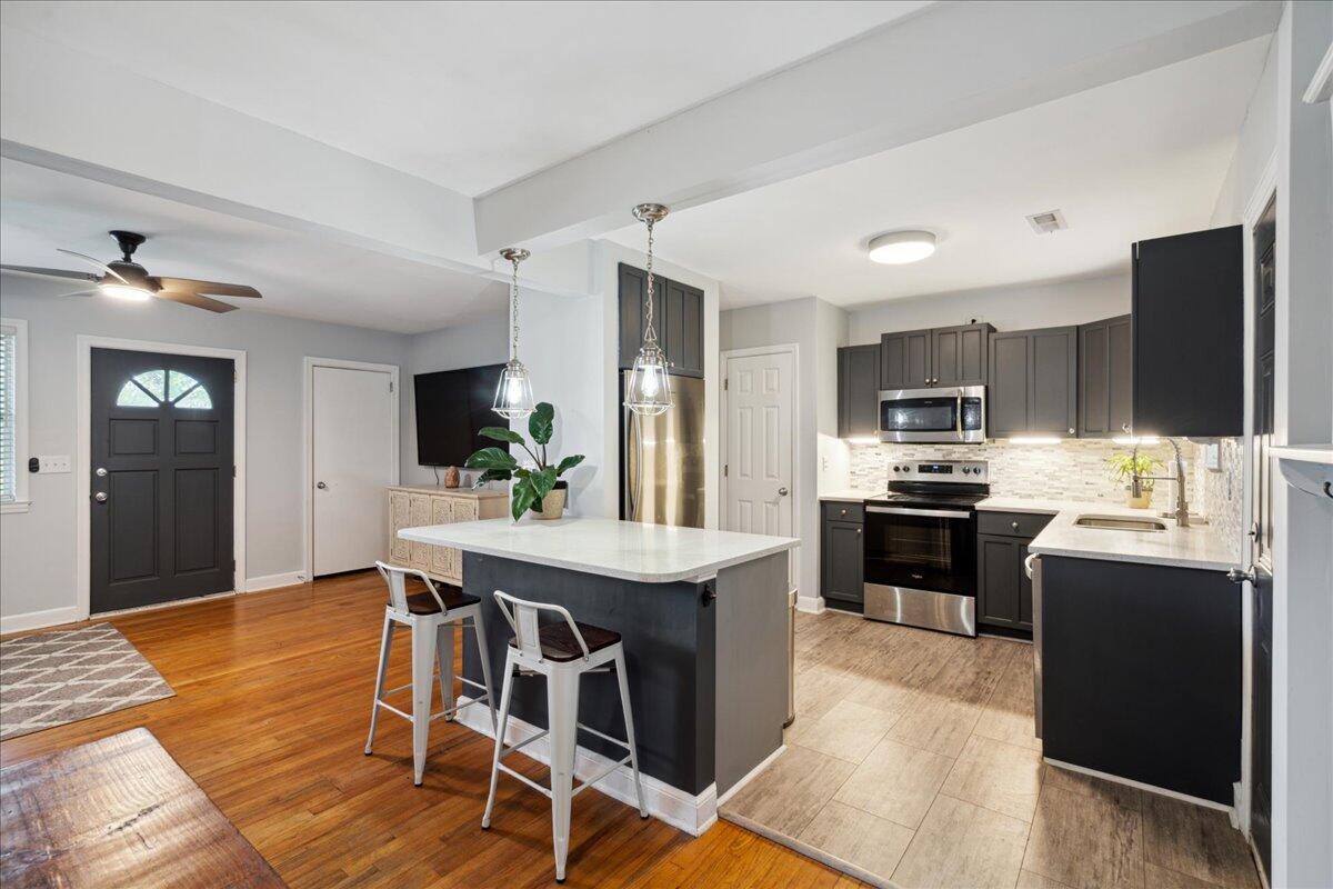 Kitchen with dark cabinets, stainless steel appliances, and a large island with bar stools.
