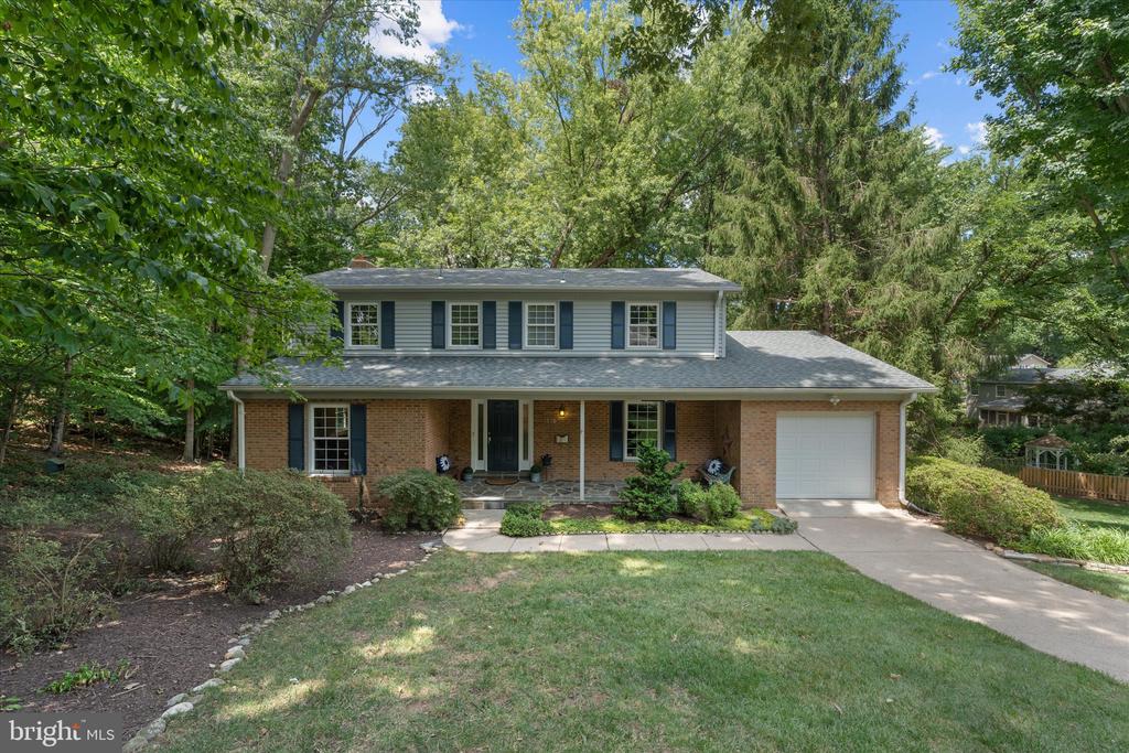 Split-level home with brick and siding, an attached garage, and mature trees.