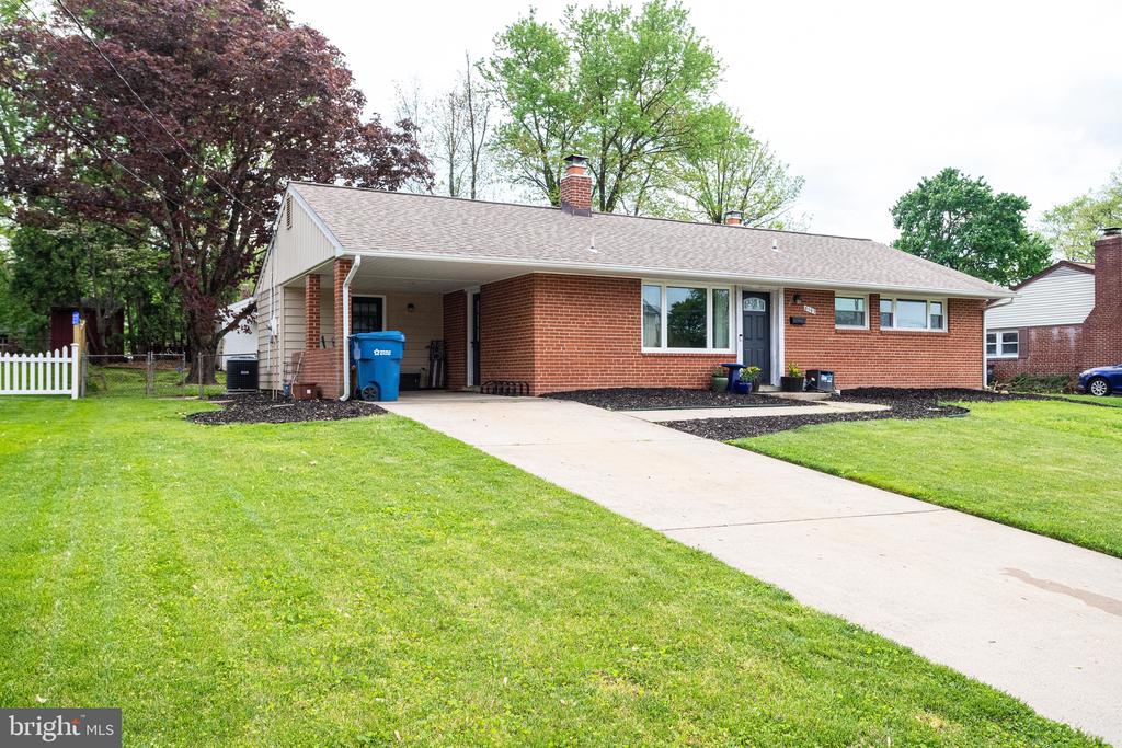 Single-story brick home with a covered carport, wide driveway, and landscaped front lawn.