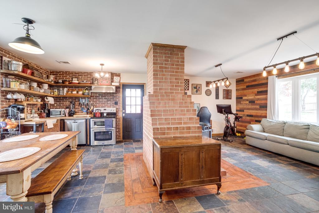 Open kitchen and living area with a central brick chimney and wood-plank accent wall.