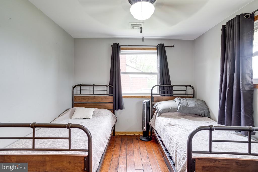 Bedroom with two single beds, dark metal frames, and hardwood floors.