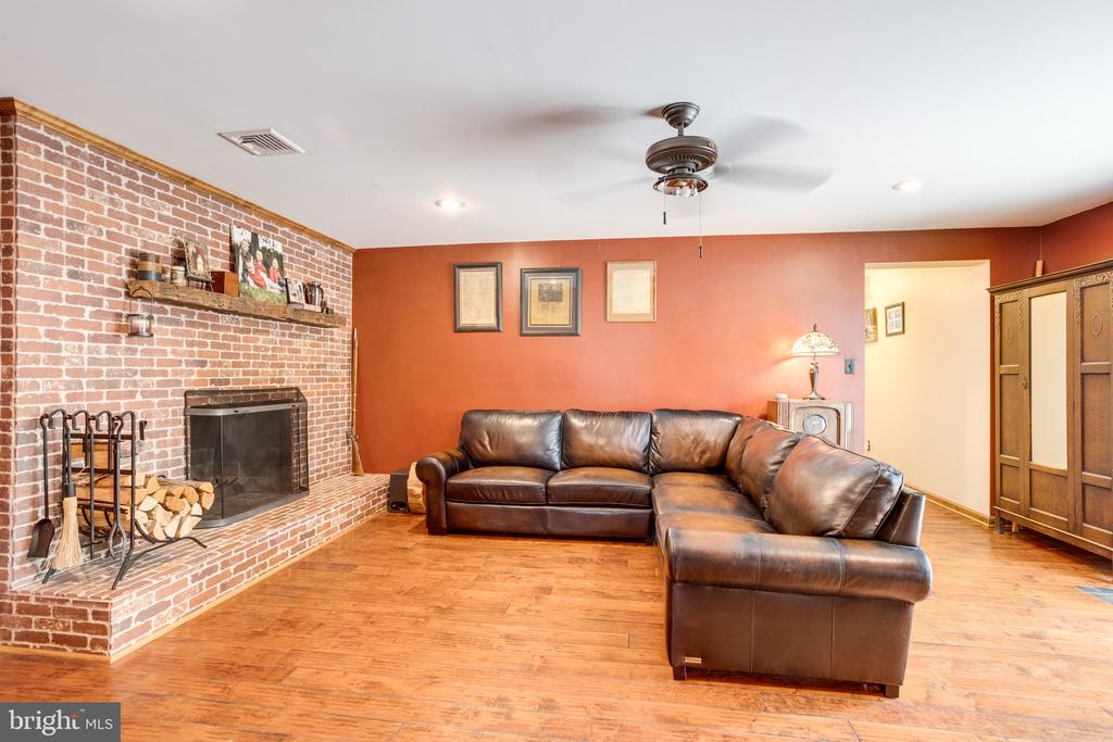 Living room with a brick fireplace, brown leather sectional, and warm wood flooring.
