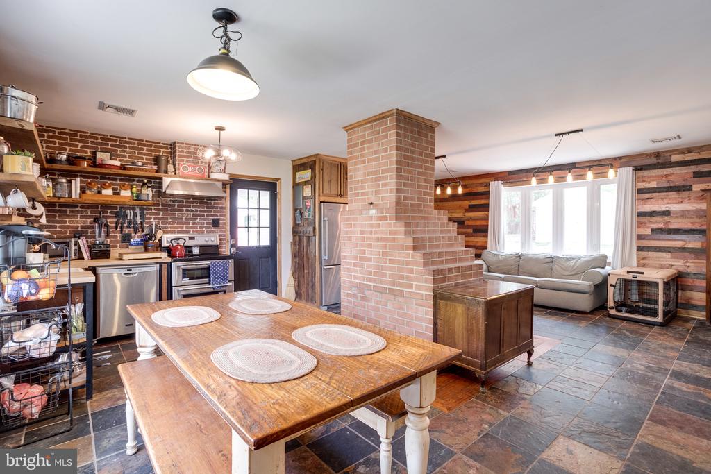 Open-plan kitchen and dining area with a prominent brick chimney and rustic wood walls.
